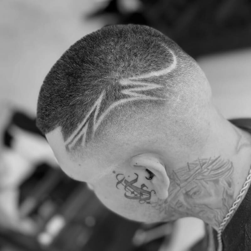 A close-up of a man with a custom design shaved into the sides, featuring sharp, geometric lines that add a unique, bold touch to the cut.