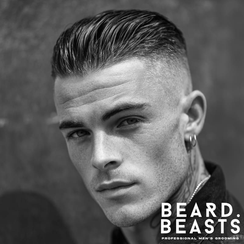 A close-up of a man with a high skin fade haircut, featuring slicked-back hair on top and a clean, sharp fade on the sides, creating a refined and polished look.
