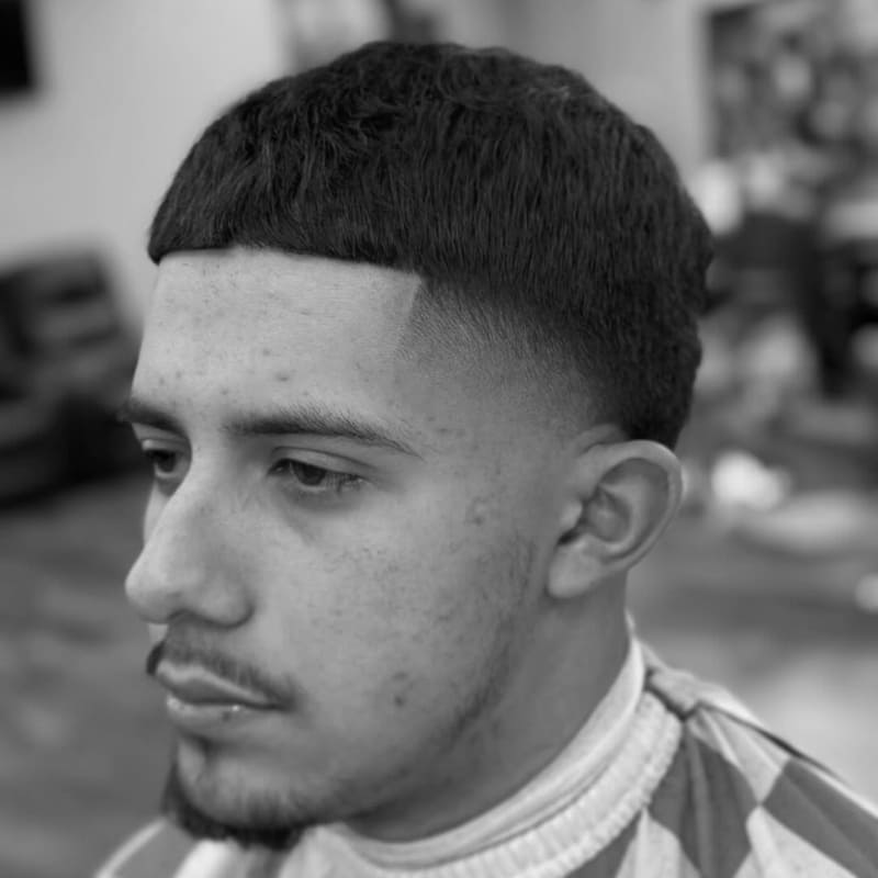 A close-up of a man with a taper fade, featuring a clean, sharp line between the short sides and longer hair on top, with a smooth, balanced finish.