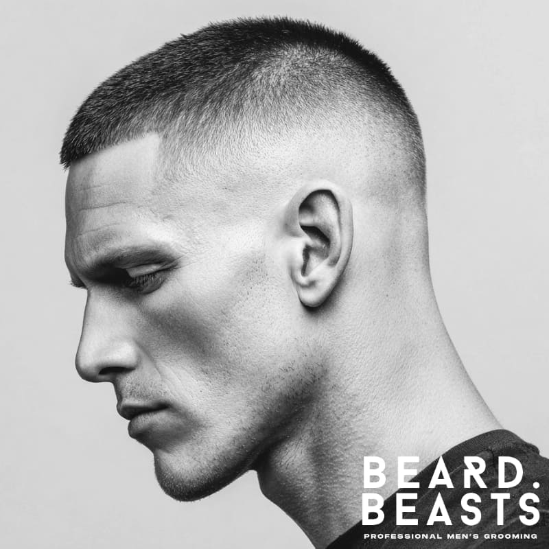 A side profile of a man with a high and tight haircut, featuring very short sides and back with a slightly longer top, creating a clean, military-inspired look with a sharp, precise finish.