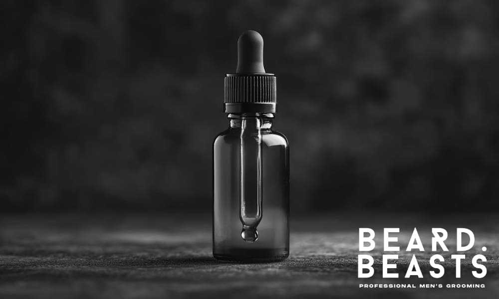 A sleek black dropper bottle of Beard Beasts Beard Oil set against a dark, textured background, with the bold Beard Beasts logo and the tagline 'Professional Men's Grooming' in the bottom right corner. The image evokes a sense of premium quality and sophistication, highlighting the brand's focus on high-end beard care products.