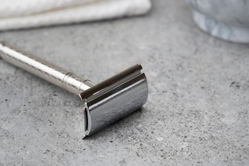 Close-up of a shaving tool, a type of single blade tool used for wet shaving, showing the blade and textured guard.