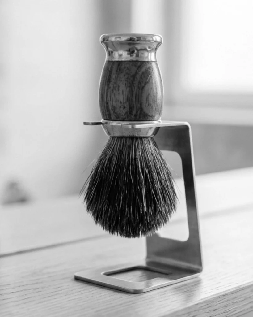 Shaving brush drying upside down on a stand in an open, well-ventilated space to help the knot dry properly.