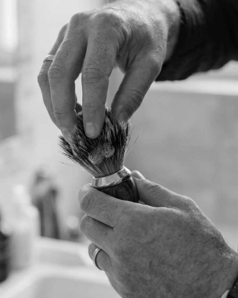Man gently working cleaner through a shaving brush knot with his fingertips without crushing or twisting the bristles.
