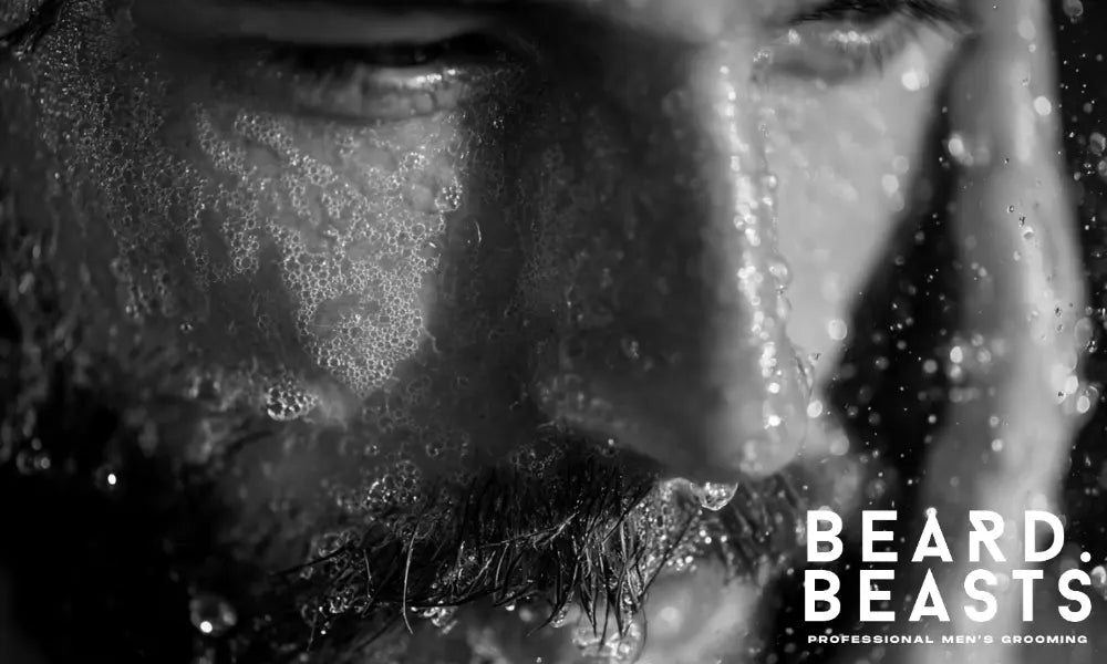 A close-up of a man thoroughly washing his beard with lather and water, representing the first and most important step before applying beard conditioner.