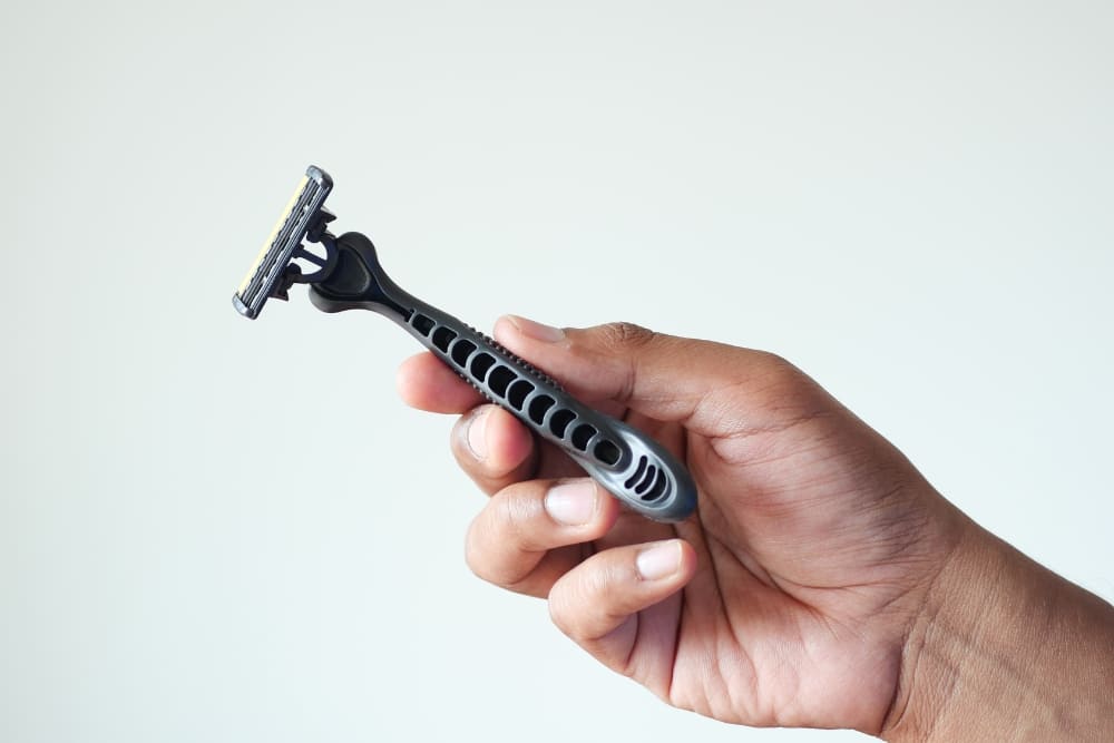 Close-up image of a hand holding a multi blade razor with a sleek black and gray handle, highlighting the modern design and efficiency of multi blade razors in the context of the single blade razor vs multi blade razor comparison.