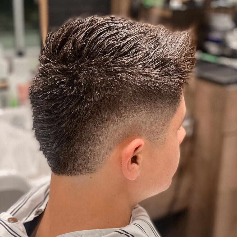 Rear view of a man with a Short Faux Hawk haircut, featuring a textured, spiky top that gradually tapers into a clean fade on the sides. This edgy and modern style adds height and definition, making it a bold choice for those looking to stand out with a trendy, low-maintenance short hairstyle.
