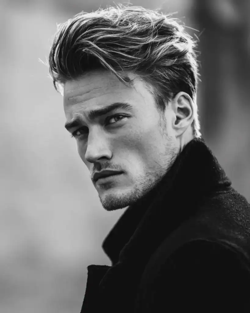 Black and white portrait of a man with a short layered flow hairstyle featuring swept-back texture and volume.