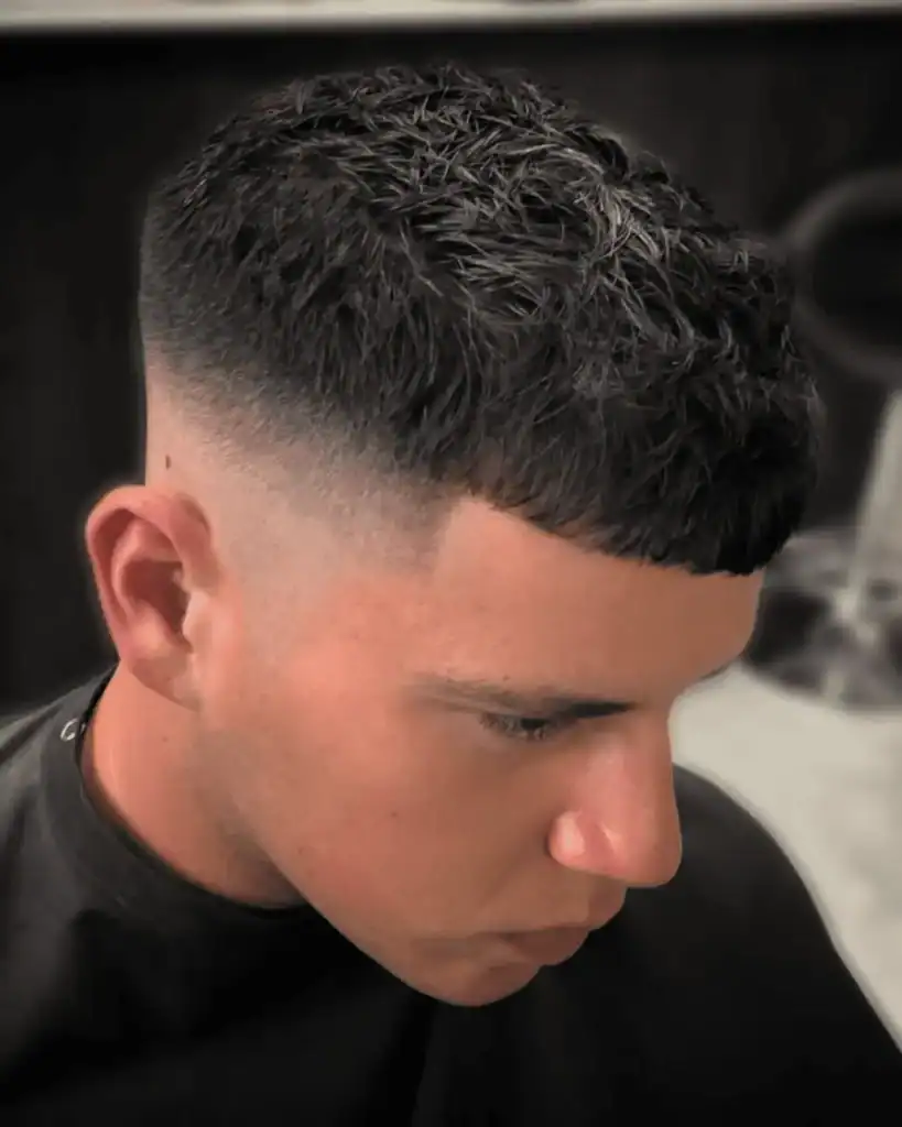 Man with a short textured French Crop haircut featuring a blunt fringe and a skin fade