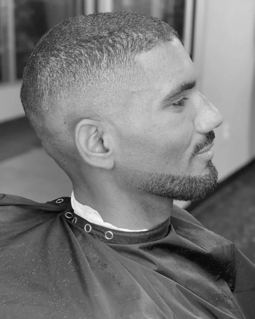 Man with a square face, Balbo beard and skin fade haircut in a barber chair