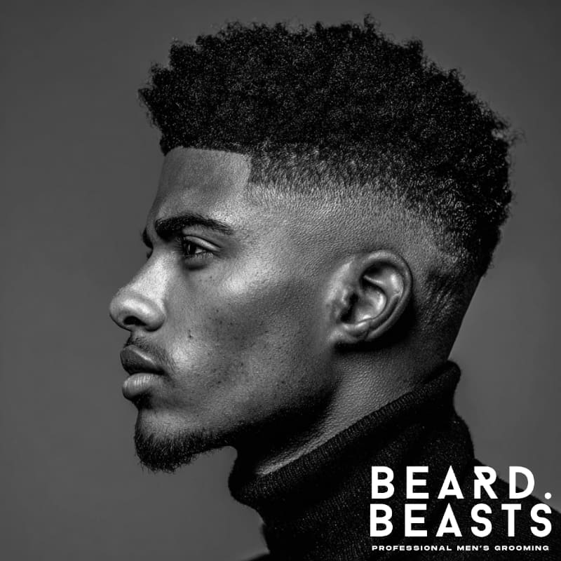 Close-up of a young man with an Afro with Tapered Sides, a stylish choice within men's short on sides, long on top haircuts. The natural afro on top is full and textured, while the tapered sides create a sharp, clean contrast, highlighting the perfect blend of tradition and modern style.