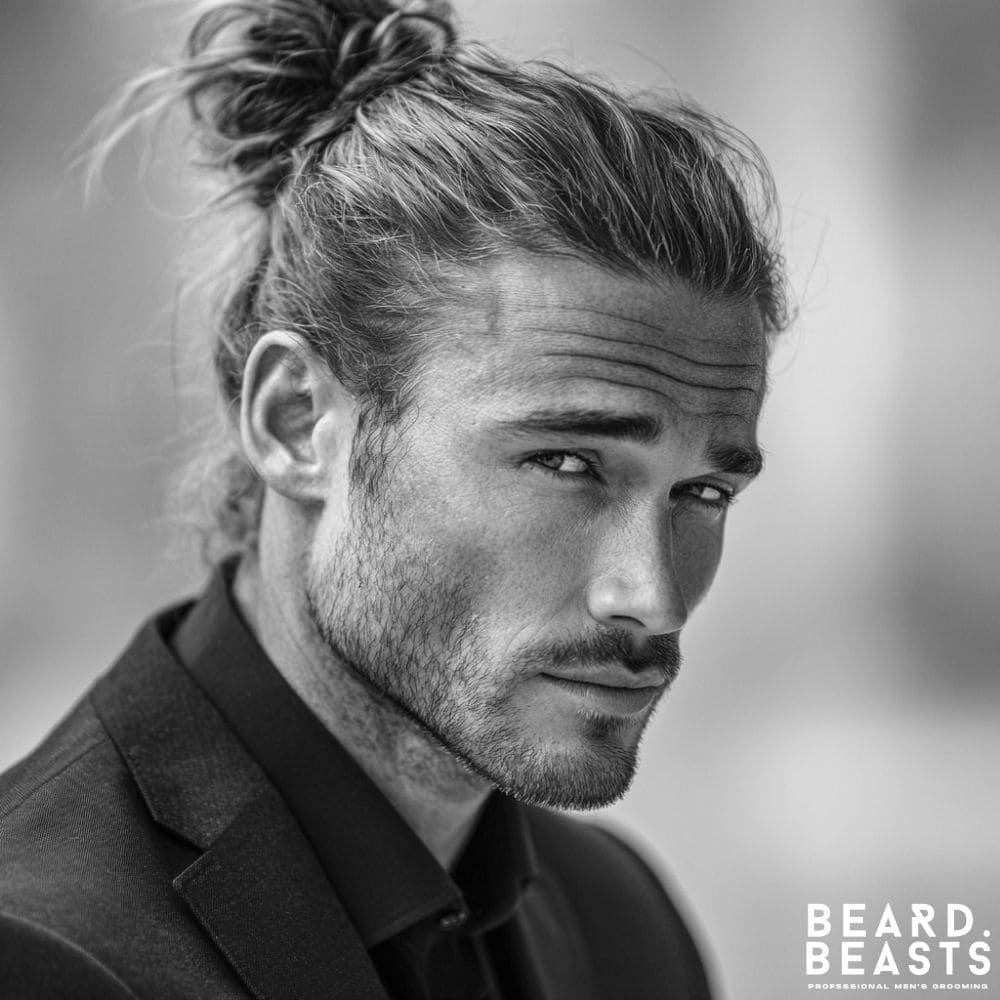 A professional man with long hair styled into a neat man bun, showcasing a modern and stylish business hairstyle.