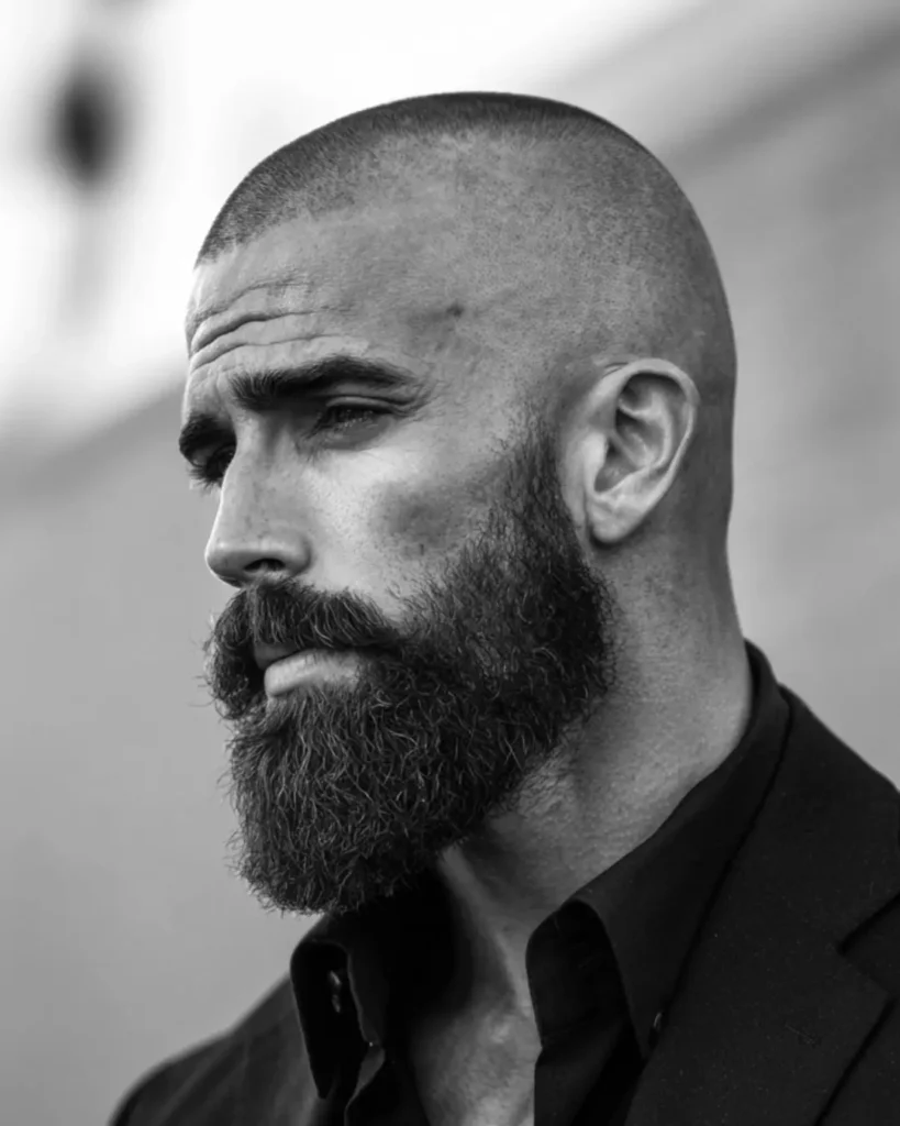 Buzz cut with a full beard, showing how a short haircut and beard can add length and definition for men with round faces.