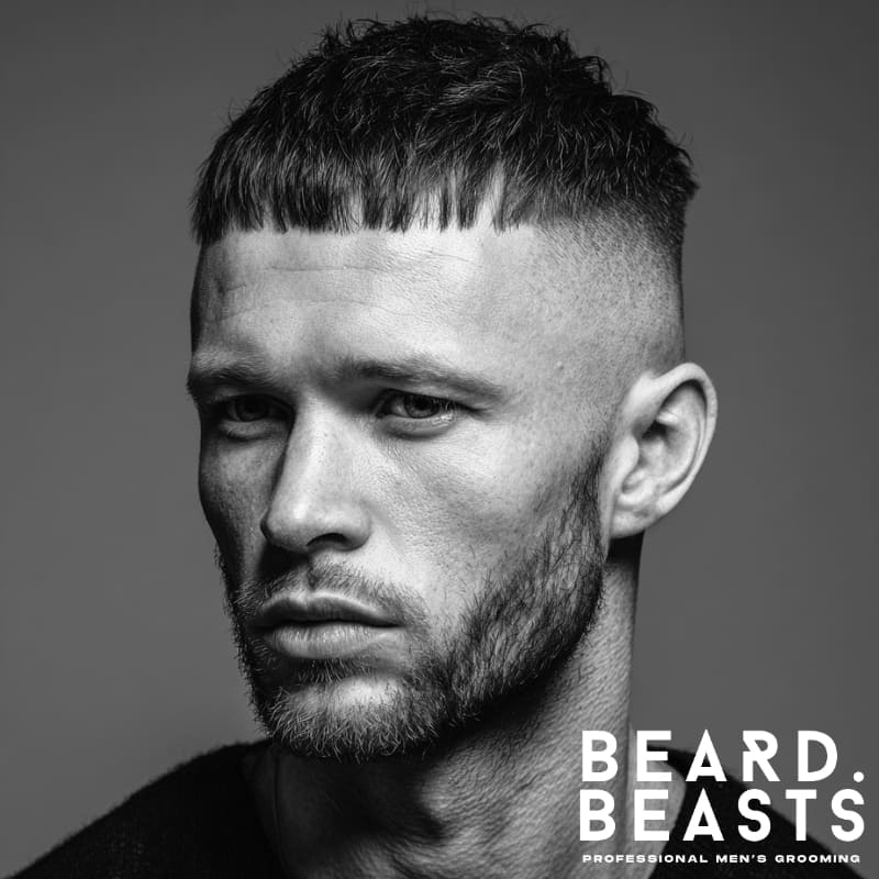 Black and white portrait of a man with a short, textured Caesar cut, a bold and modern hairstyle for men with square face shapes.