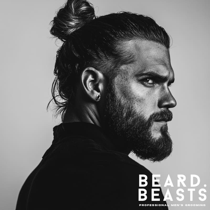 Black and white profile of a man with a classic high man bun and full beard, featuring slicked-back hair and a clean, timeless look.