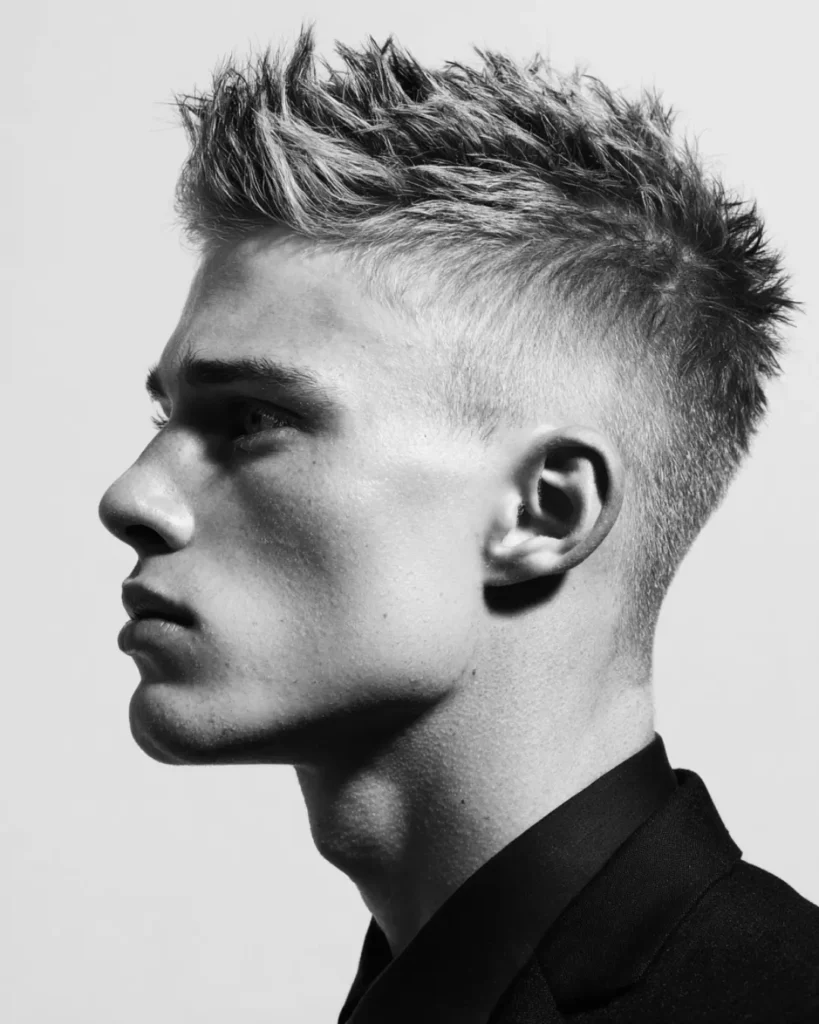 Faux hawk haircut with lifted textured hair through the middle and short faded sides, showing a medium hairstyle option for men with round faces.