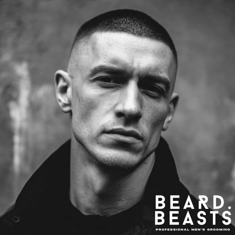 Black and white portrait of a man with a sharp high and tight haircut, a masculine and low-maintenance style for men with square face shapes.