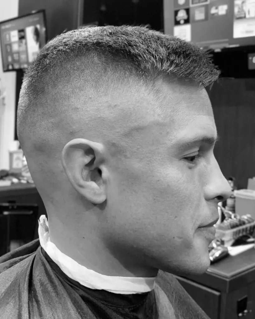 High and tight haircut with faded sides and short textured hair on top, showing a short hairstyle option for men with round faces.