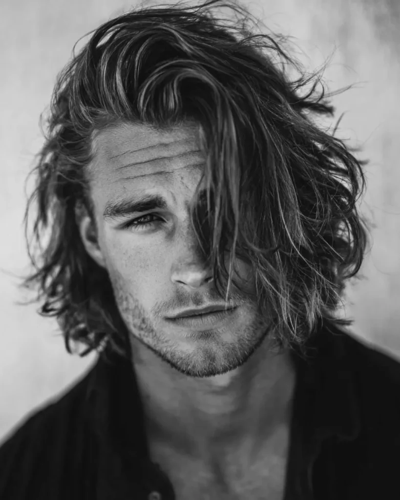 Layered medium-length hair with long textured layers and side-swept movement, showing a longer hairstyle option for men with round faces.
