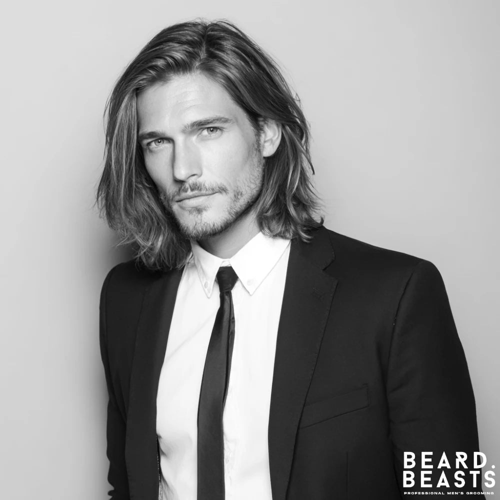 A professional man in a suit and tie with well-maintained, shoulder-length straight hair. His hair is parted to the side, showcasing a sophisticated and modern way to wear long hairstyles in a professional environment.