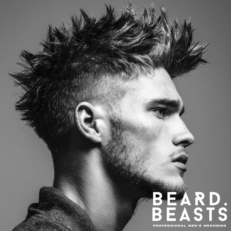 Side profile of a man with a faux hawk haircut, featuring spiked textured hair on top and faded short sides. This short on sides, long on top hairstyle delivers bold height, sharp definition, and a modern edgy look.
