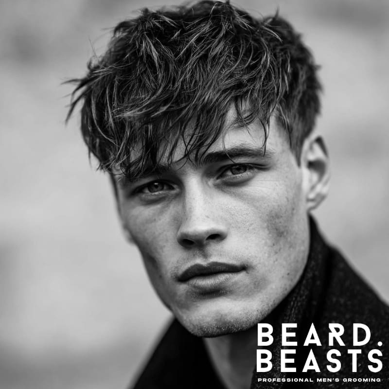 Close-up of a man with a messy fringe haircut, also known as a textured crop, a relaxed and low-maintenance hairstyle for men with square face shapes.