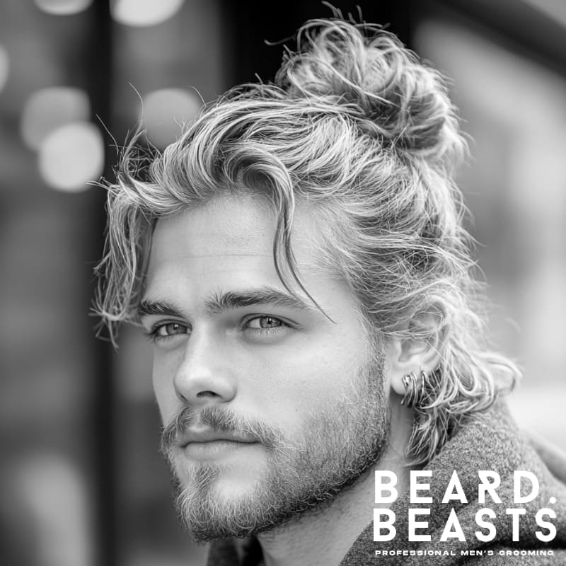 Close-up of a man with a messy man bun and wavy blond hair, featuring loose strands and a relaxed finish—ideal for a casual men’s hairstyle.