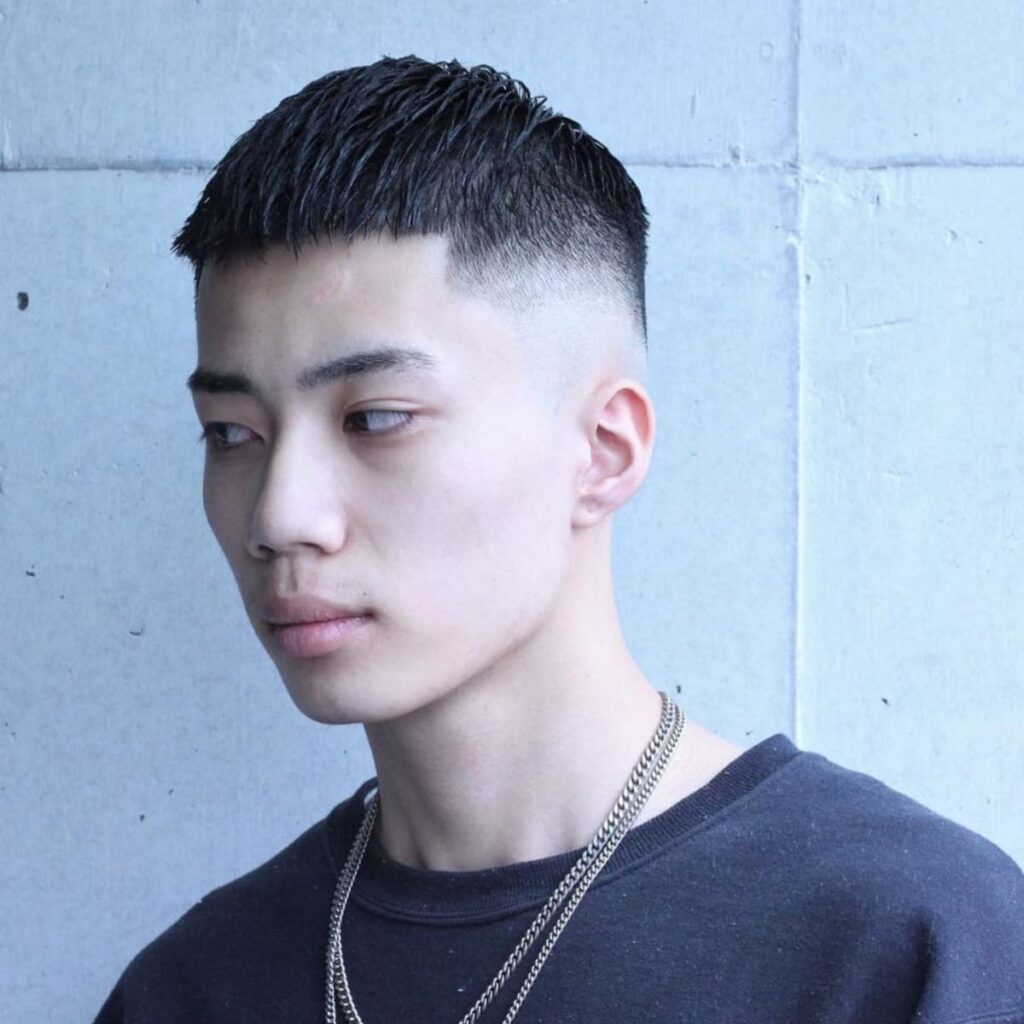 Side profile of a young man with a clean crew cut featuring a smooth taper. The haircut combines a short, textured top with a high taper down to the skin, creating a minimalist yet stylish look. This cut accentuates the jawline and adds structure to the face, ideal for a simple, modern style that’s easy to maintain.