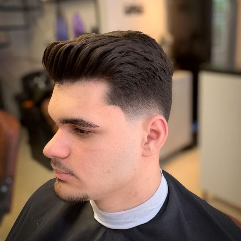 Side profile of a classic low fade quiff hairstyle with a clean fade around the ears and voluminous top. Perfect example of a low fade quiff for men, featuring a sharp, polished look suitable for various face shapes and occasions.