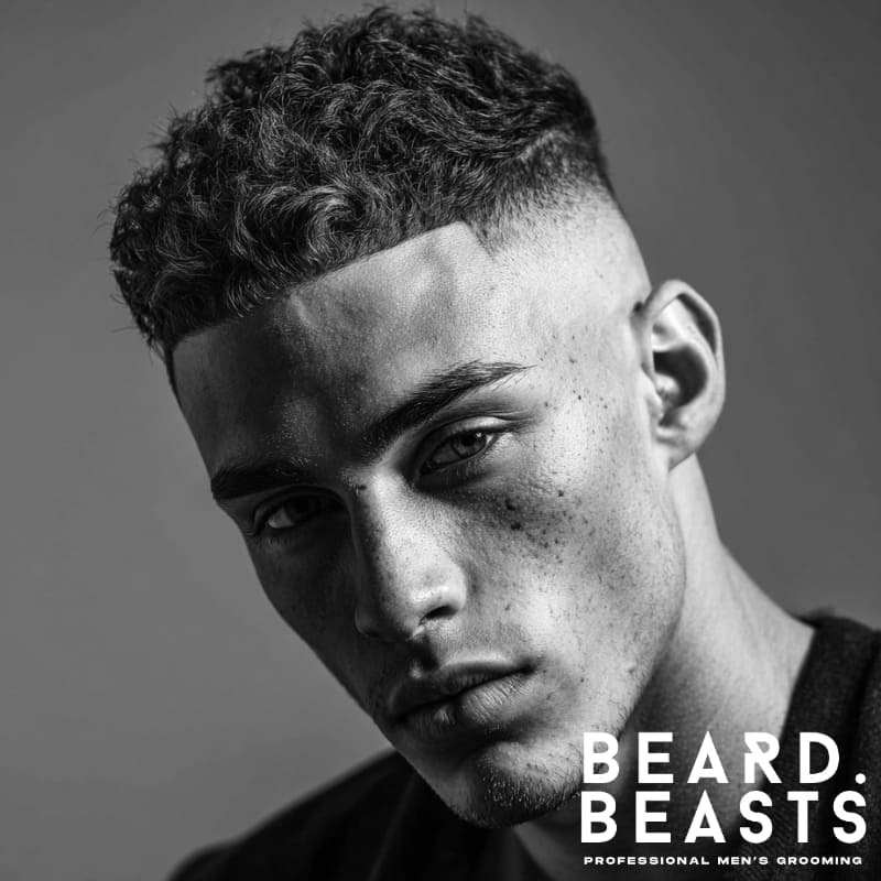 Skin fade with textured top and curly hair, featuring a clean fade on the sides and voluminous curls on top.