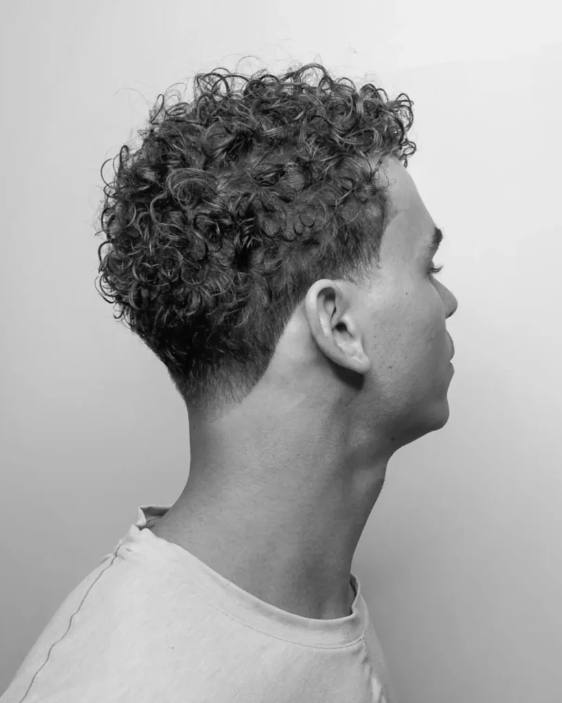 curly hair fade with shaved line up at the hairline, side profile black and white