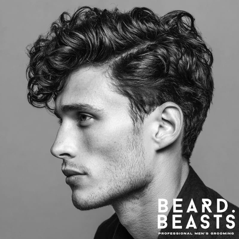 Man with curly hair styled into a side part quiff—soft curls on top and short tapered sides.