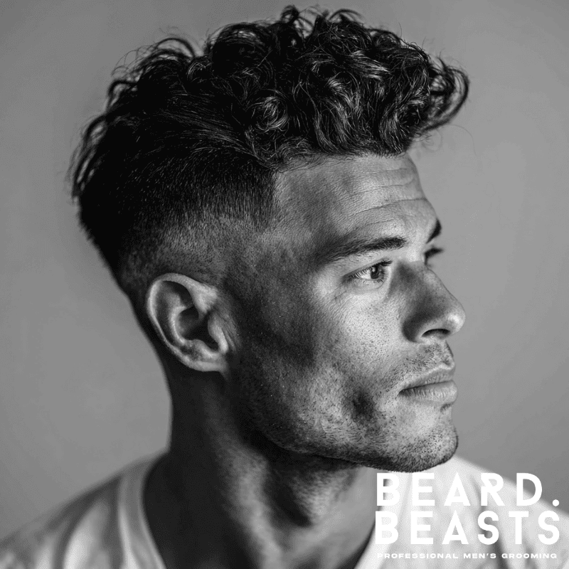 Curly skin fade pompadour with voluminous, natural curls on top and sharp fade on the sides, creating a bold, modern contrast.