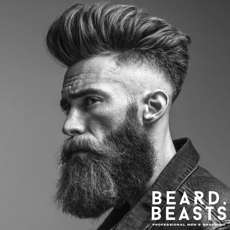 High skin fade pompadour with voluminous top styled back and sharp fade on the sides, paired with a full beard for a bold, masculine look.