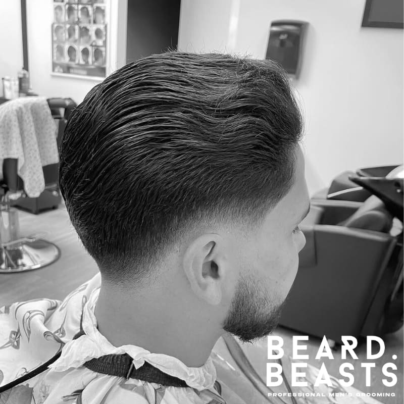 A clean and sharp low blend with a slicked-back hairstyle, showcasing a polished and professional look. The hair is styled neatly with a smooth, refined finish, perfect for a sleek, modern appearance.