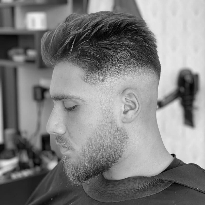 A clean mid blend hairstyle featuring a textured top, styled for a modern, fresh look. The blend is sharp and smooth, with a natural volume on top that adds a dynamic, well-groomed appearance.