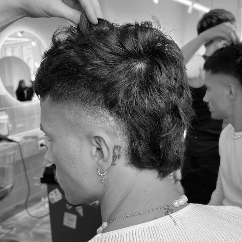 A bold mohawk skin fade hairstyle with shaved sides and textured volume on top. The cut blends the sharp contrast of the fade with spiked hair for an edgy, standout look.