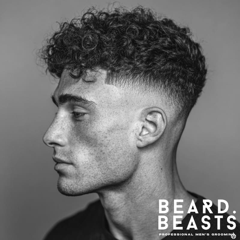 Skin fade with drop fade and curly hair on top, showcasing a sharp, defined fade with natural curls for a dynamic, modern style.
