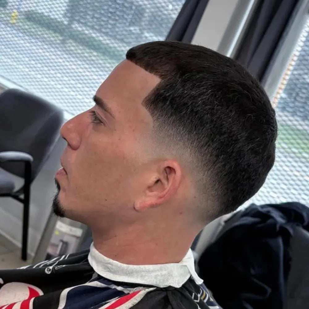 Man with a mid drop fade buzz cut, featuring a curved fade that follows the head shape and a sharp hairline, highlighting a sleek style for 2025.