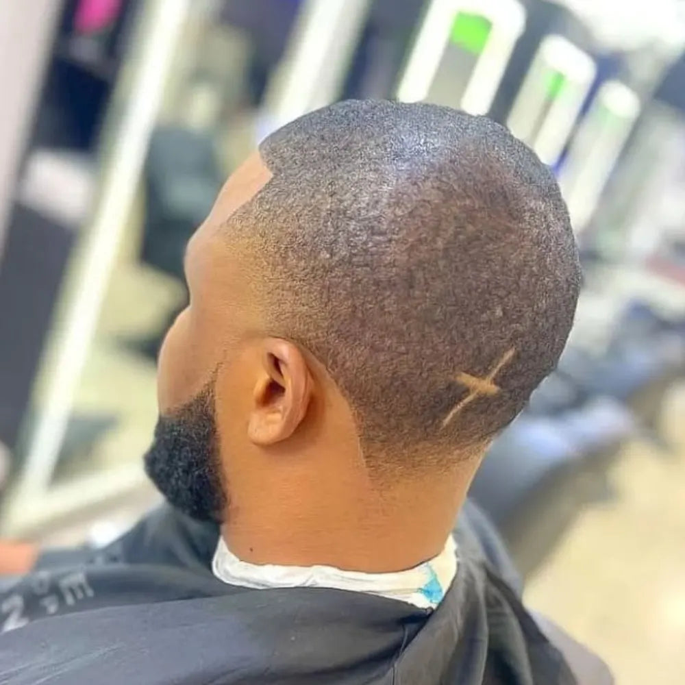 Man with a mid taper fade buzz cut, featuring softly blended sides and a subtle design at the back for a refined yet modern look.