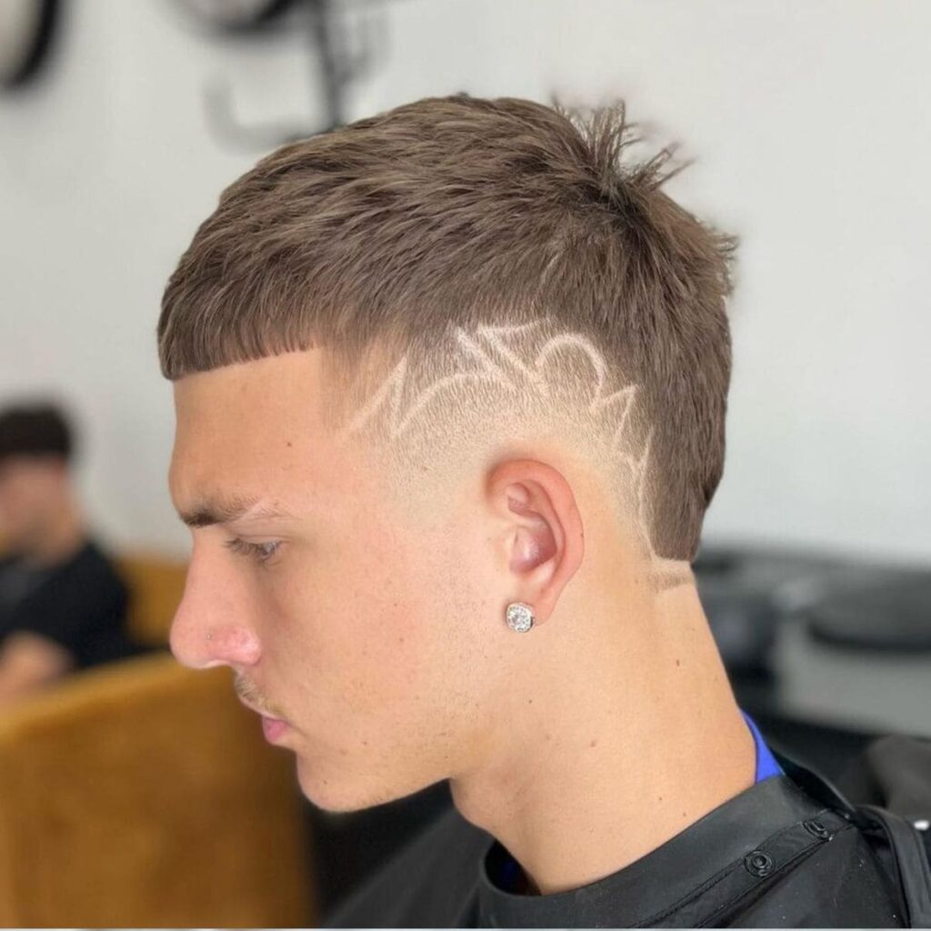 Short textured crop with burst fade and hair design detail on the sides.