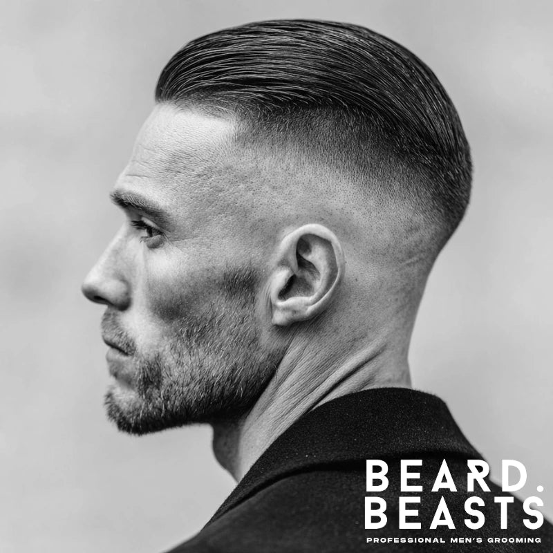 Bald drop fade with slicked-back hair, featuring a smooth, sleek top and clean, sharp fade around the ears. This style offers a polished, structured appearance, ideal for professional settings or refined looks.