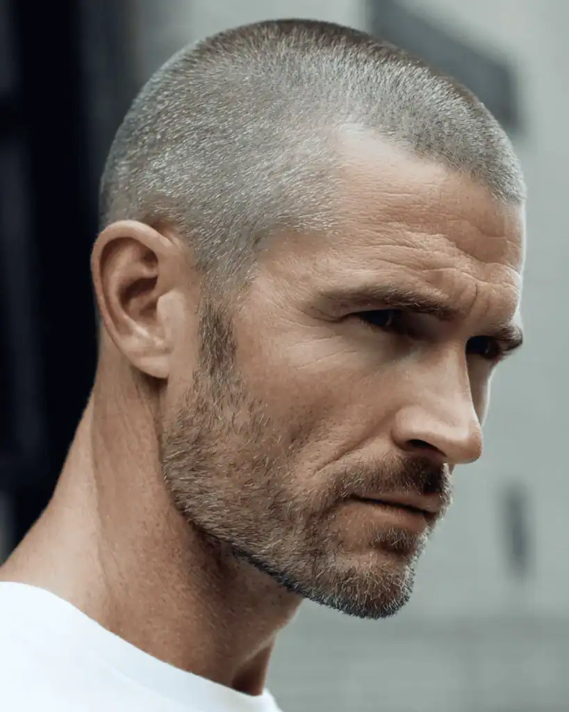 Side profile of a fit man over 40 with a burr cut hairstyle, showing a uniform #2 guard length with soft stubble texture.