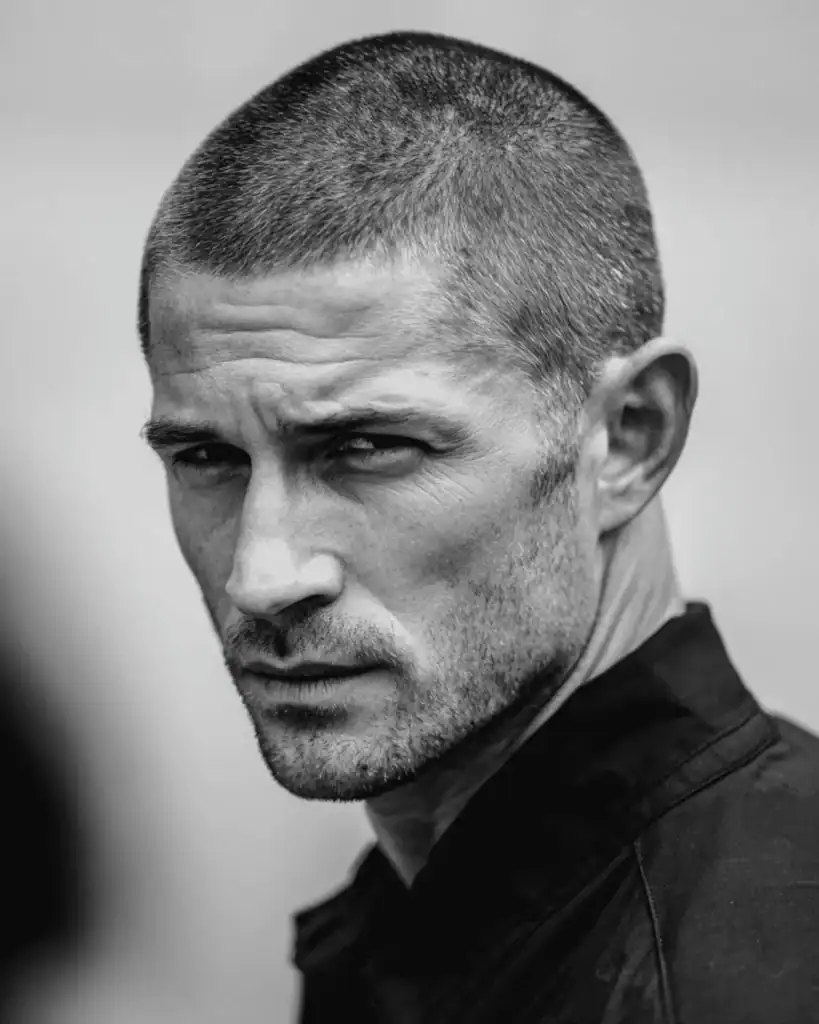 Black and white portrait of a serious man over 40 with a butch cut hairstyle and beard, showing a uniform #4 guard length.