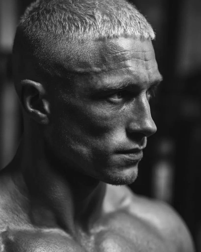 Caesar cut haircut on a bodybuilder with blonde hair and short horizontal fringe, side profile