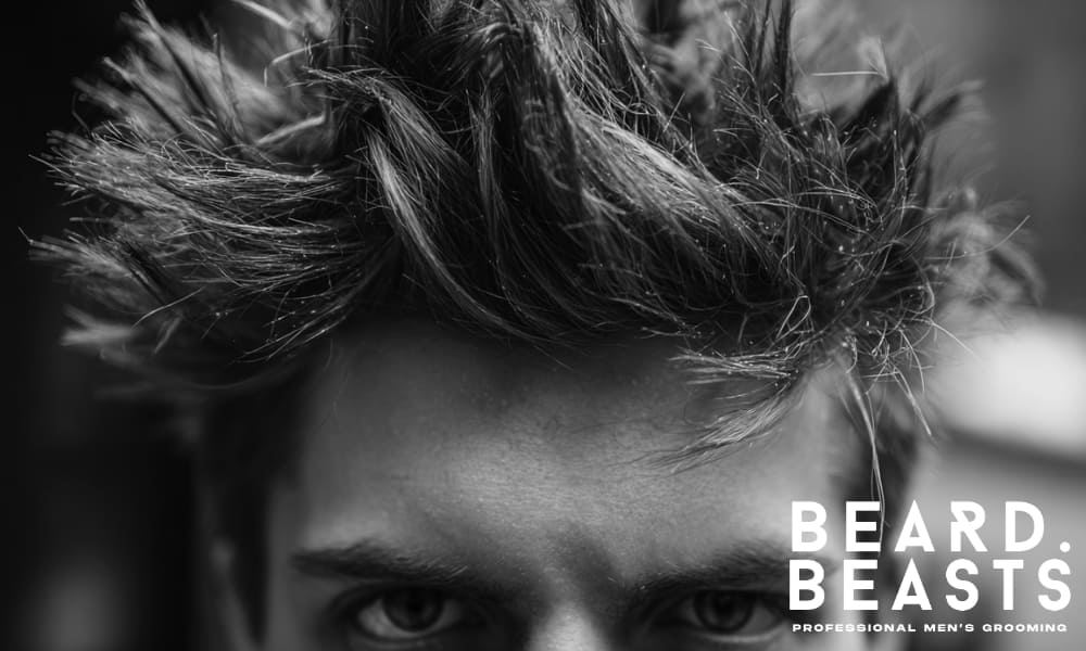 Close-up of a male model’s hair, showing textured, voluminous spikes. The hairstyle is natural, creating a bold and defined look.