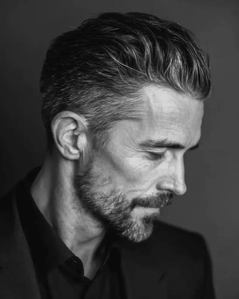 Side profile of a distinguished man over 40 with an executive contour haircut, featuring hair swept back and to the side in a natural, polished flow.