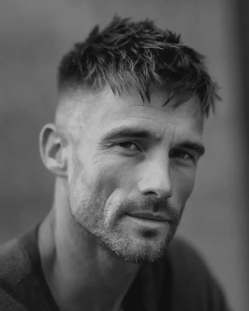 Close-up of a stylish man over 40 with a French Crop haircut, featuring high faded sides and a textured, messy fringe styled forward.