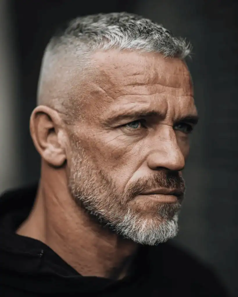 Side profile of a confident man over 40 with a high and tight haircut, featuring high shaved sides and a short, textured grey top.