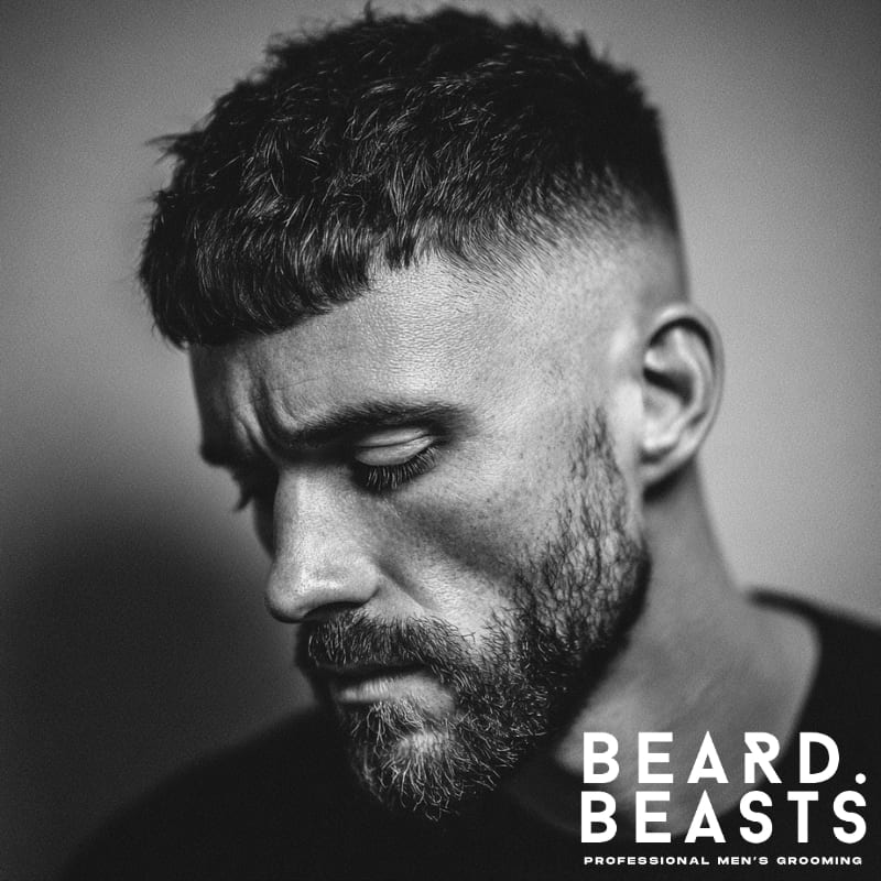 High fade French crop with a short fringe and full beard, creating a sharp, bold contrast. Ideal for men seeking a clean yet rugged modern look with a well-defined fade.